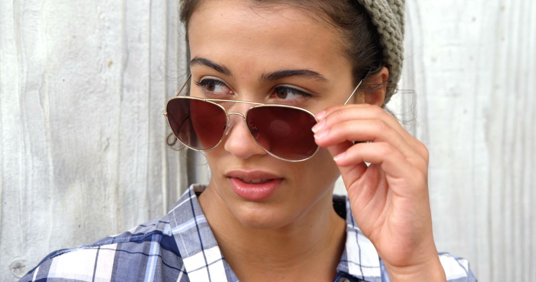 Female with Brown Sunglasses Touching Glasses Looking Aside - Free Images, Stock Photos and Pictures on Pikwizard.com