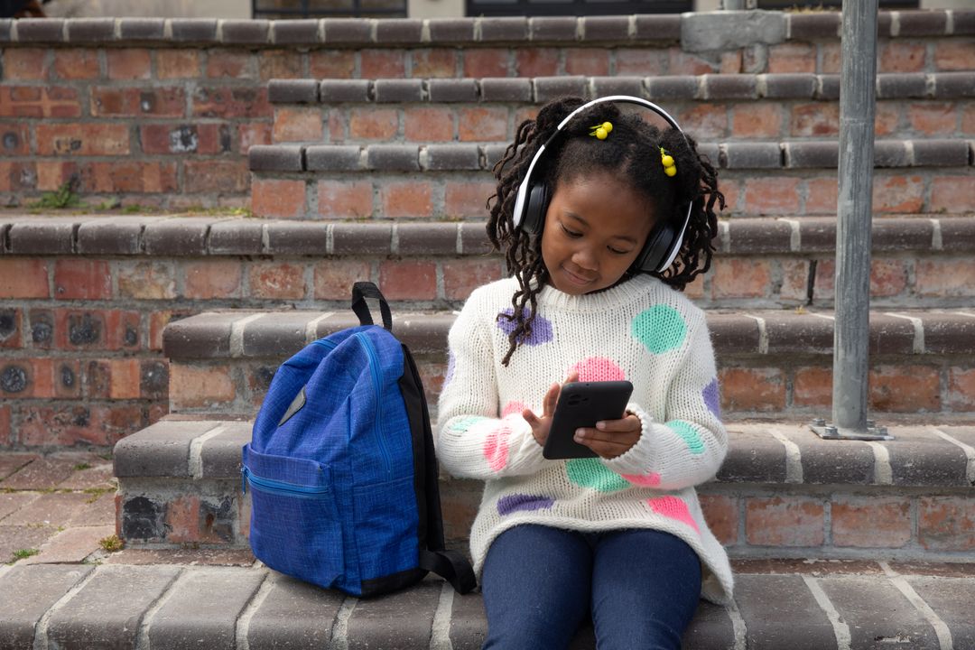 Young Girl with Headphones Using Tablet on Outdoor Steps