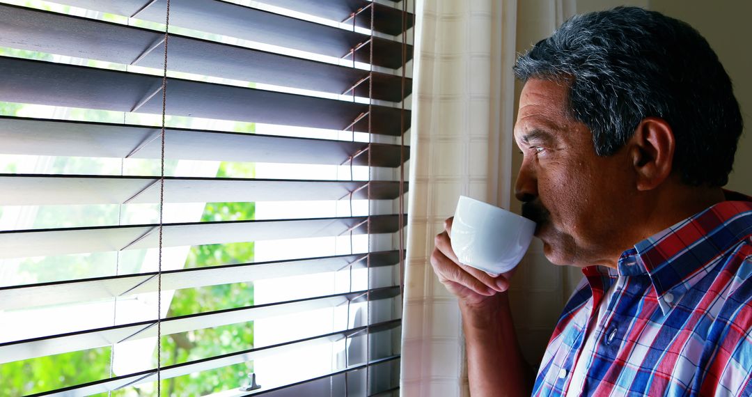 Senior Man Drinking Coffee at Home Looking Through Window Blinds - Free Images, Stock Photos and Pictures on Pikwizard.com