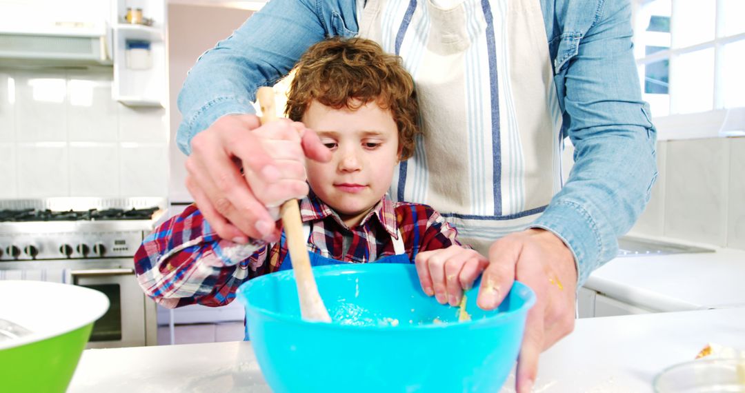 Young boy and father mixing dough in kitchen together - Free Images, Stock Photos and Pictures on Pikwizard.com