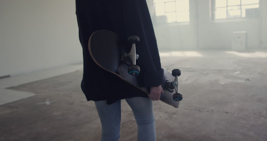 Person Holding Skateboard in Spacious Room with Light through Windows - Free Images, Stock Photos and Pictures on Pikwizard.com