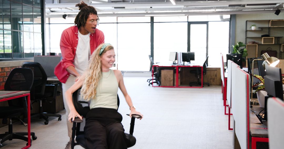 Colleagues Having Fun in Modern Office with Swivel Chair Ride