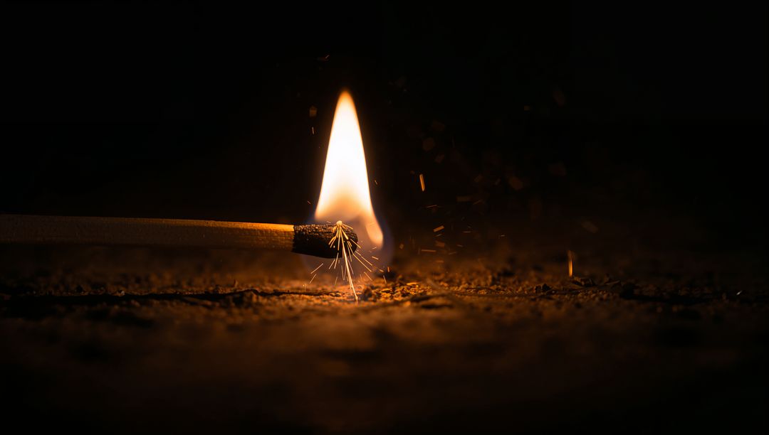 Burning Matchstick Igniting Golden Sparks on Dark Gritty Surface Closeup Macro High-Contrast