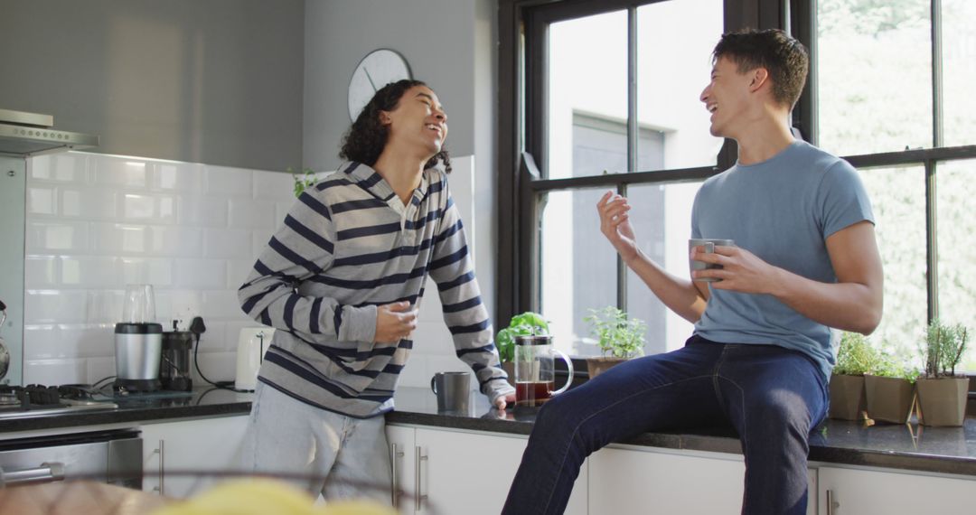 Two Friends Sharing Laughter While Having Coffee in Modern Kitchen - Free Images, Stock Photos and Pictures on Pikwizard.com