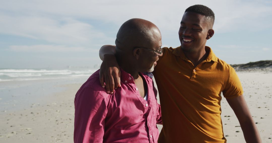 Young Man and Older Man Smiling and Embracing on Beach - Free Images, Stock Photos and Pictures on Pikwizard.com