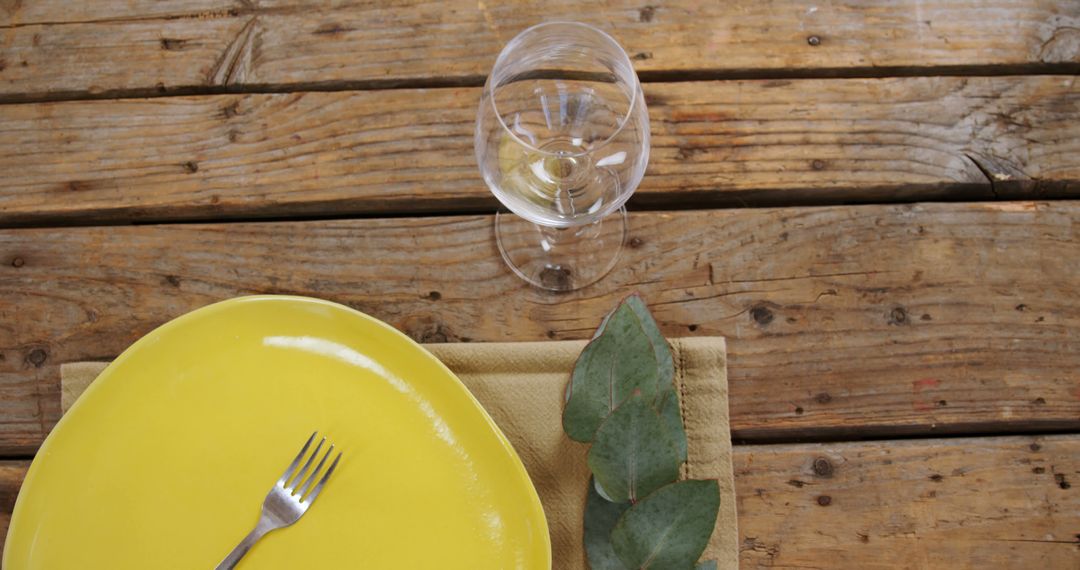 Empty yellow plate with wine glass on rustic wooden table outdoor - Free Images, Stock Photos and Pictures on Pikwizard.com