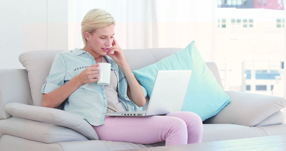 Woman Working on Laptop at Home, Holding Mug and Talking on Phone - Free Images, Stock Photos and Pictures on Pikwizard.com