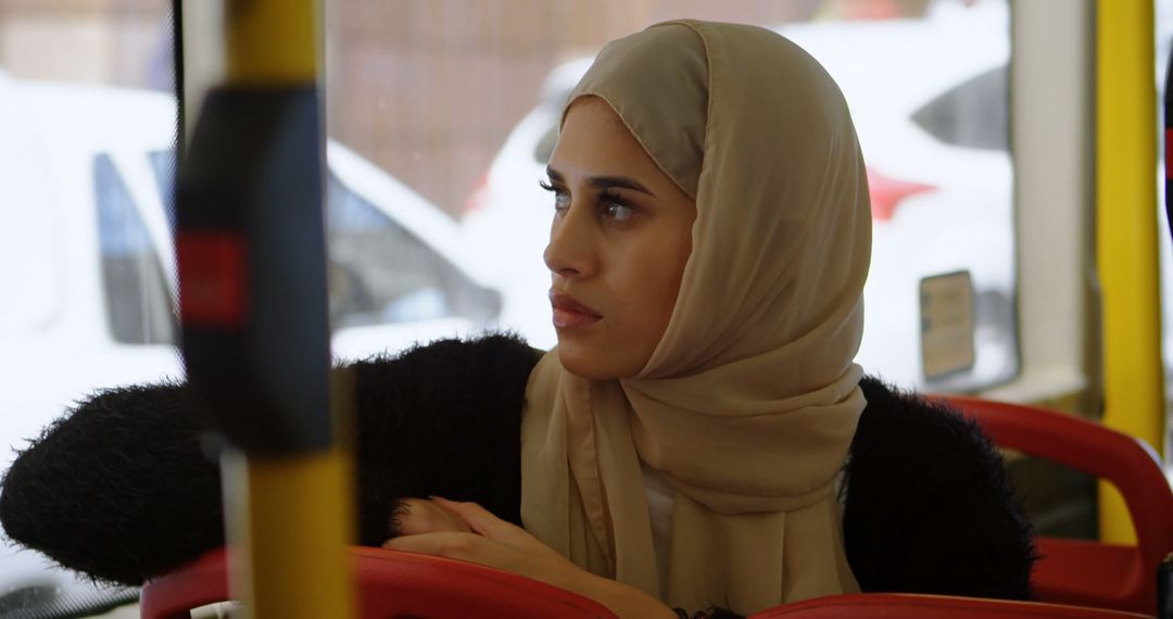 Contemplative Woman Wearing Hijab Sitting on Public Bus - Free Images, Stock Photos and Pictures on Pikwizard.com