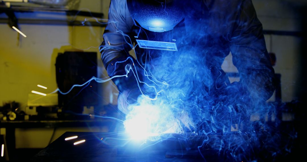 Welder Working with Intense Blue Sparks in Industrial Workshop
