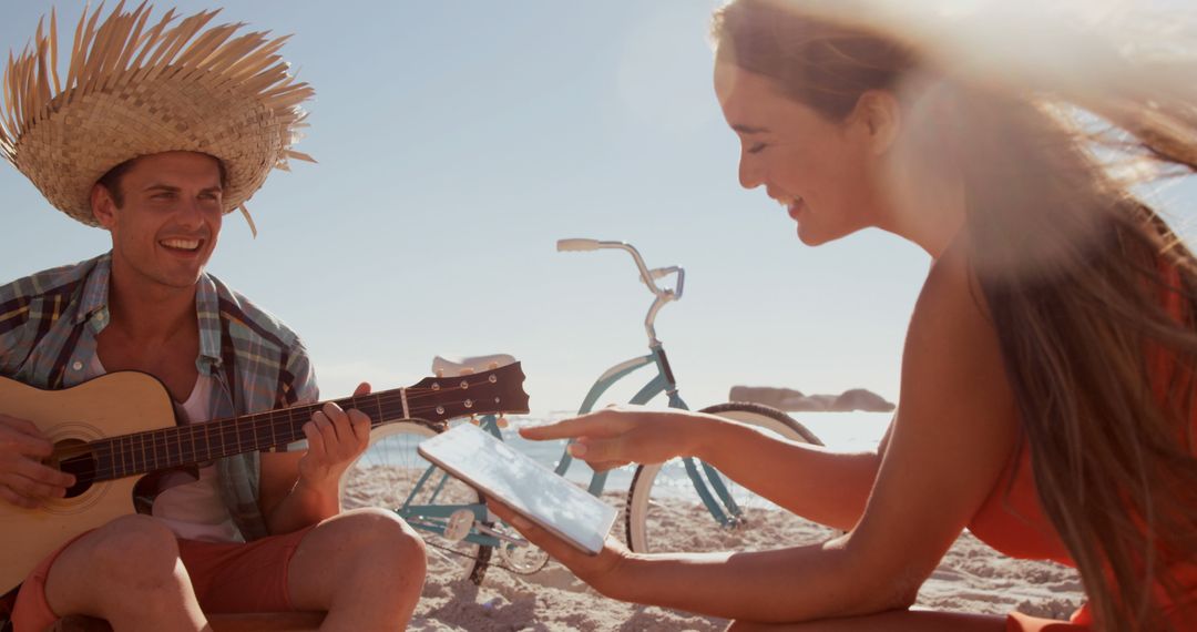 Friends Enjoying Beach Day with Guitar and Tablet Under Sunny Sky - Free Images, Stock Photos and Pictures on Pikwizard.com