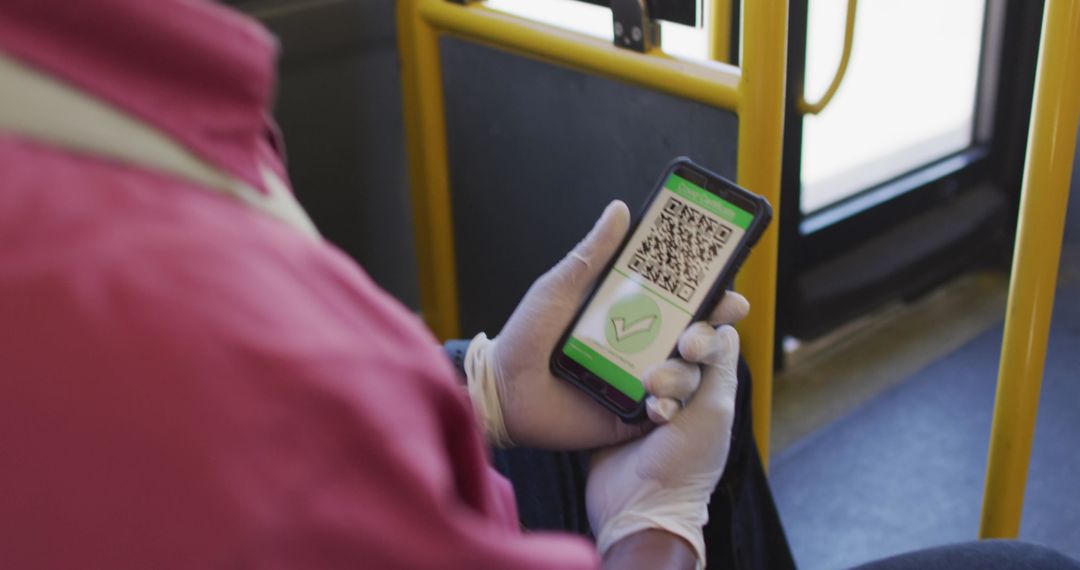 Man Wearing Gloves Using Smartphone with COVID-19 Passport on Bus