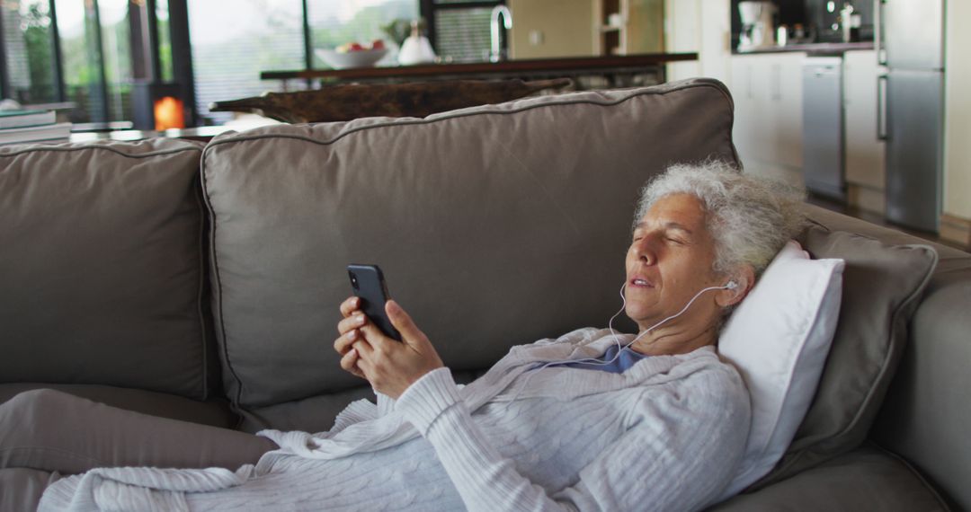 Senior Woman Relaxing on Sofa Listening to Music with Earphones - Free Images, Stock Photos and Pictures on Pikwizard.com