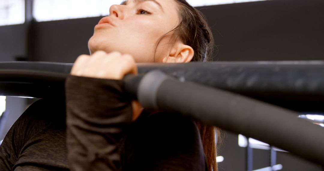 Caucasian Woman Focused While Doing Pull-Ups in Fitness Studio
