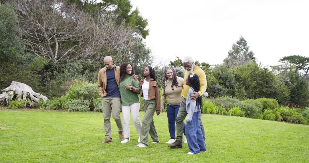 Multi-generational family walking together on green lawn in park sharing joyful moment