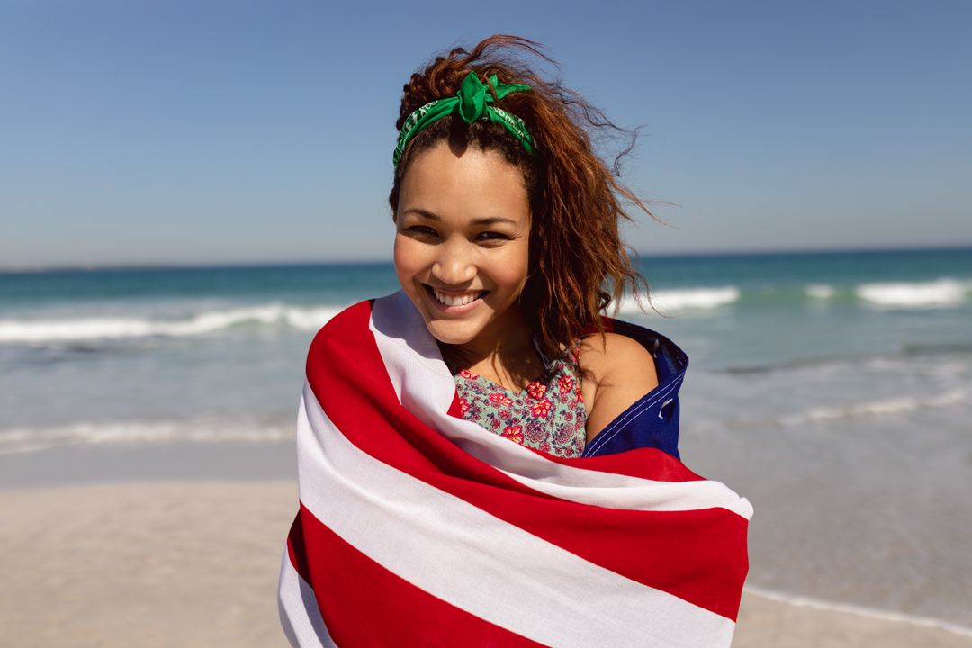 Biracial woman wrapped in towel, standing on beach, smiling - Free Images, Stock Photos and Pictures on Pikwizard.com