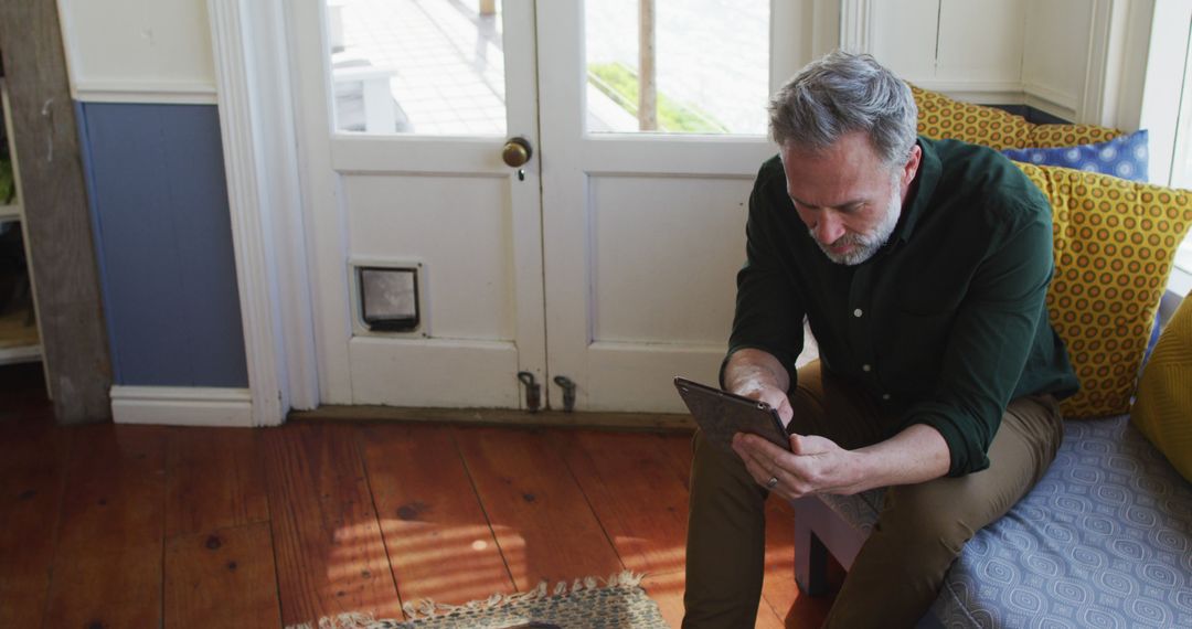 Mature Man Reading a Tablet on a Cozy Home Sofa - Free Images, Stock Photos and Pictures on Pikwizard.com