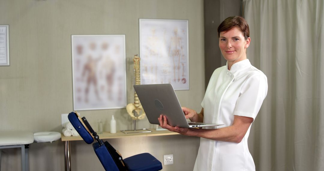 Confident Chiropractor Holding Laptop in Clinic - Free Images, Stock Photos and Pictures on Pikwizard.com