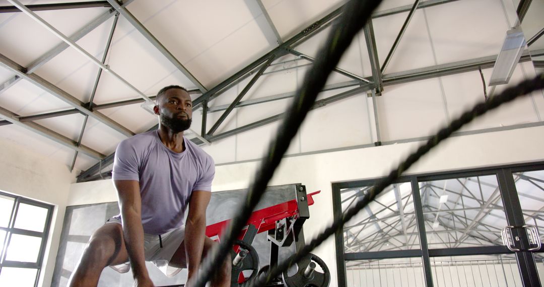 Man Engaging in Battle Rope Workout in Modern Gym Environment