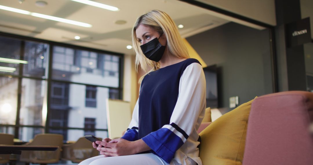 Blonde Woman Wearing Face Mask Working on Smartphone in Modern Office - Free Images, Stock Photos and Pictures on Pikwizard.com