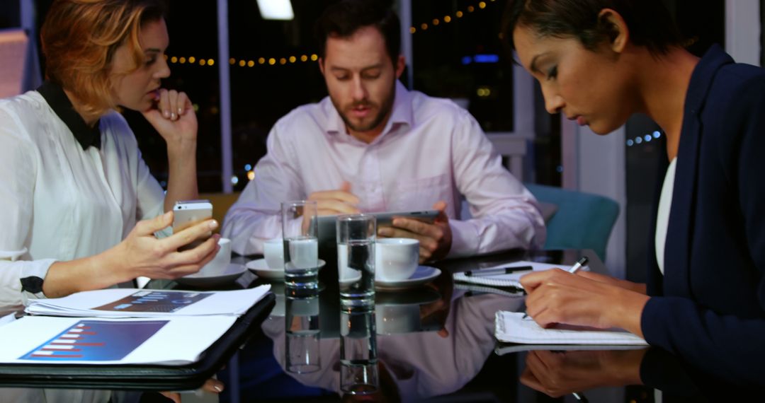 Business Team Meeting at Night with Documents and Tablets - Free Images, Stock Photos and Pictures on Pikwizard.com