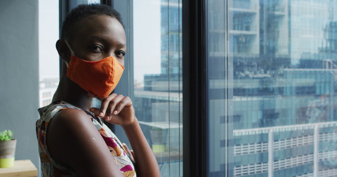 Confident African Woman Wearing Mask by Window in Office Building - Free Images, Stock Photos and Pictures on Pikwizard.com