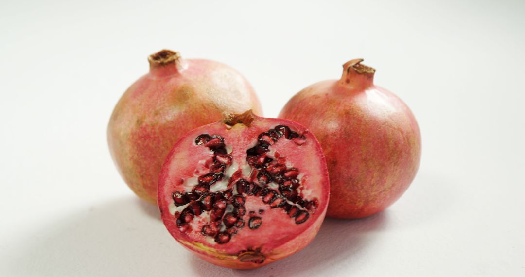 Fresh Pomegranates with Sliced Half on White Background - Free Images, Stock Photos and Pictures on Pikwizard.com