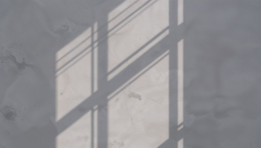 Window Shadow Grid Casting on Weathered Plaster Wall in Soft Daylight