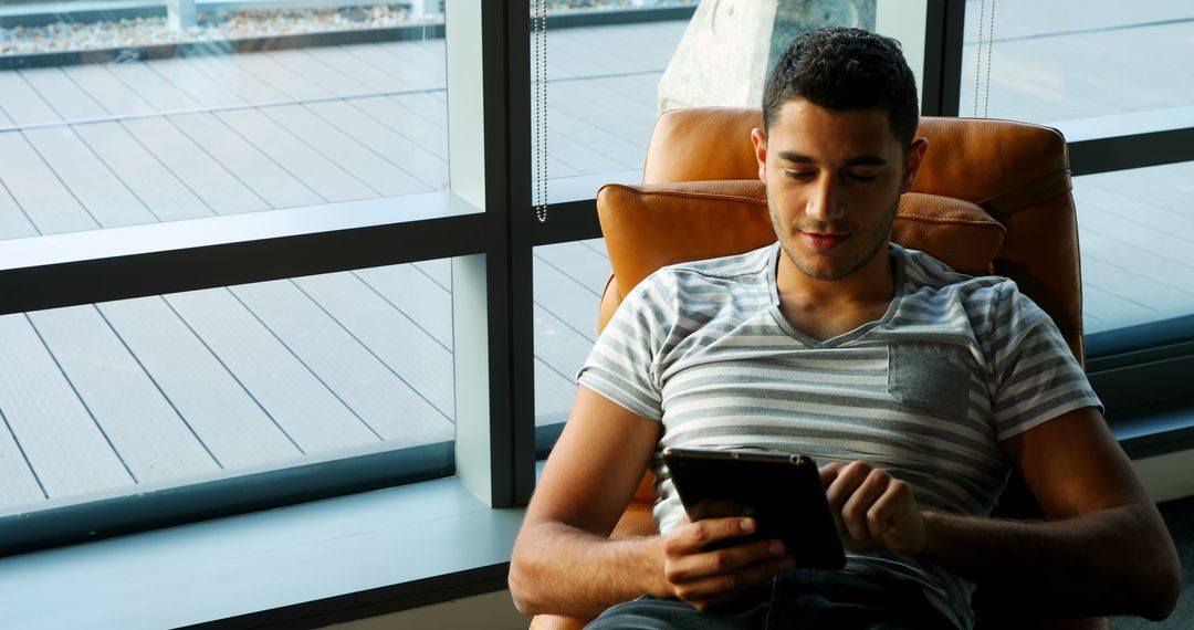 Young man relaxing indoors while using digital tablet - Free Images, Stock Photos and Pictures on Pikwizard.com