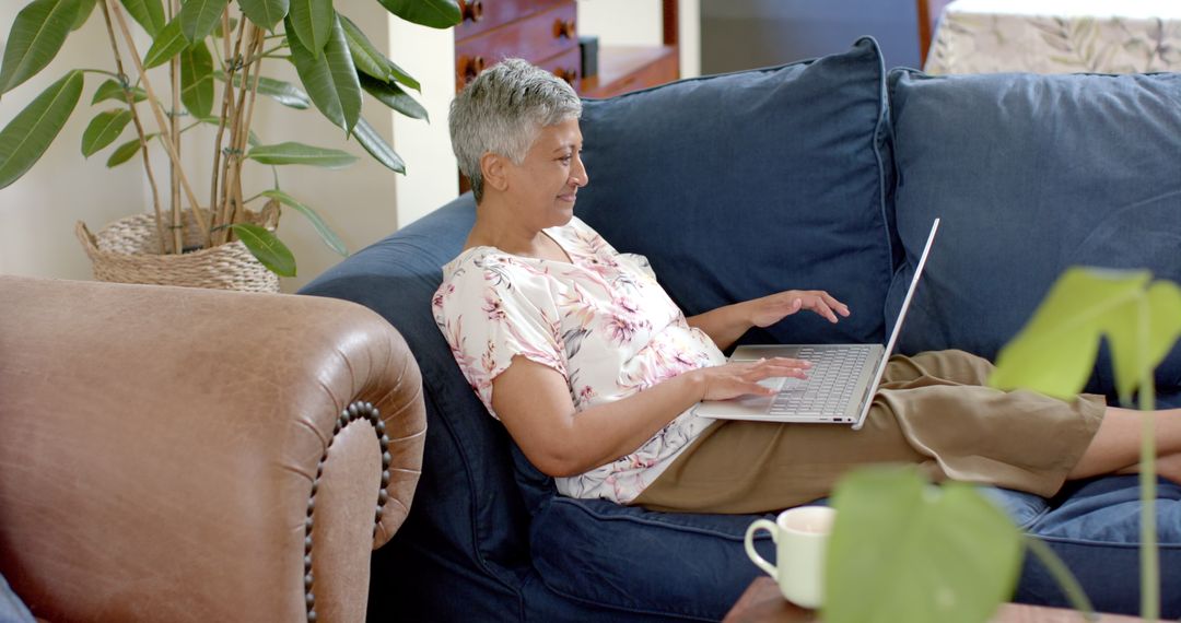 Senior Woman Relaxing on Couch Using Laptop At Home, Embracing Technology