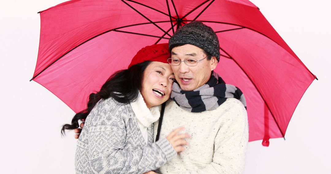 Senior Asian Couple Smiling Under Red Umbrella in Winter Attire - Free Images, Stock Photos and Pictures on Pikwizard.com