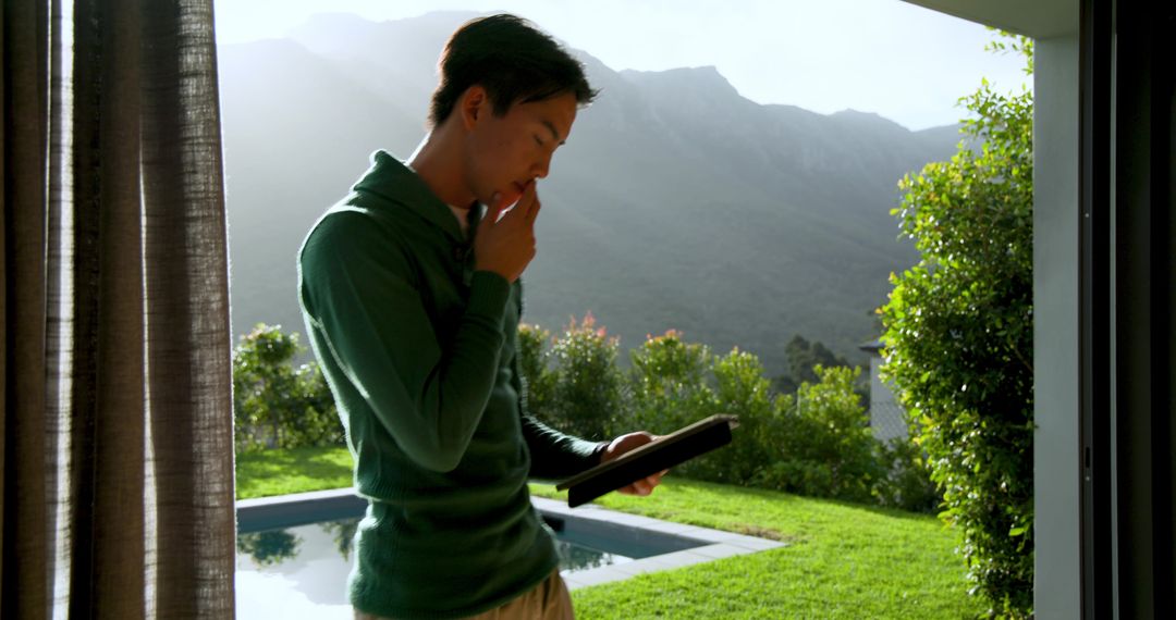 Man Contemplating in Modern Home with Tablet by Poolside