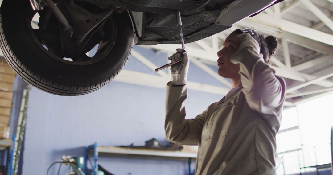 Female Mechanic Inspecting Vehicle on Lift in Auto Repair Shop - Free Images, Stock Photos and Pictures on Pikwizard.com