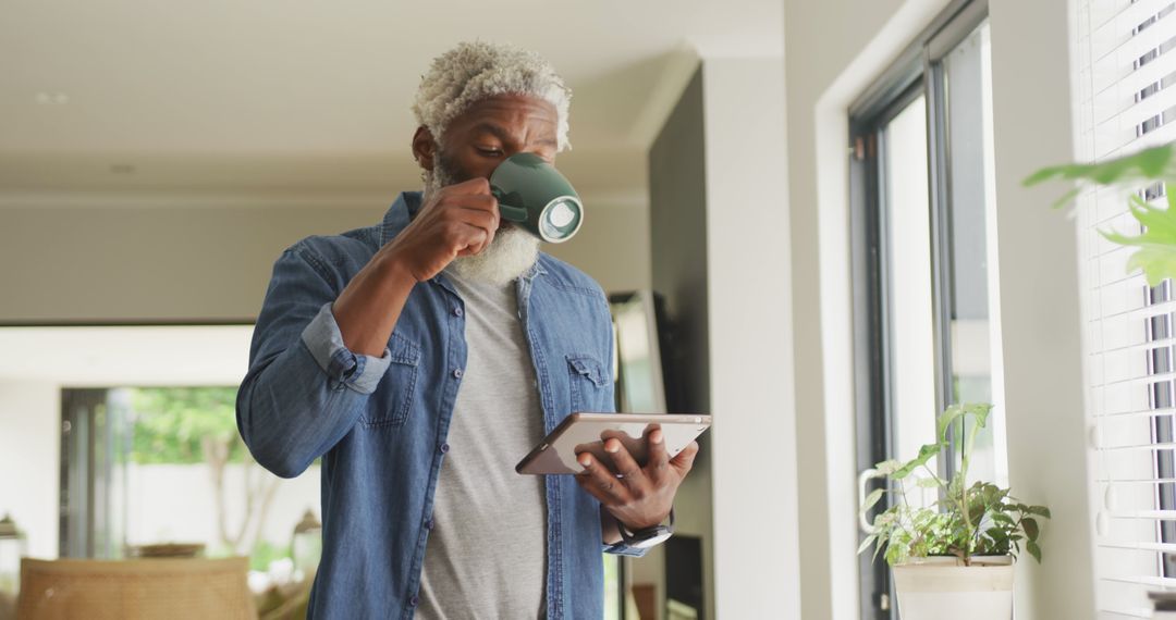 Senior Man Drinking Coffee While Using Tablet in Modern Home - Free Images, Stock Photos and Pictures on Pikwizard.com