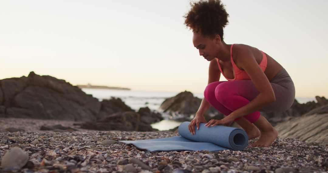 Woman Rolling Yoga Mat on Rocky Beach at Sunset - Free Images, Stock Photos and Pictures on Pikwizard.com