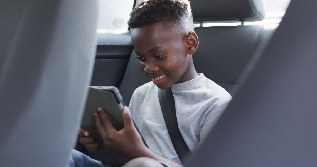 Laughing Child Engaged with Tablet in Car Backseat