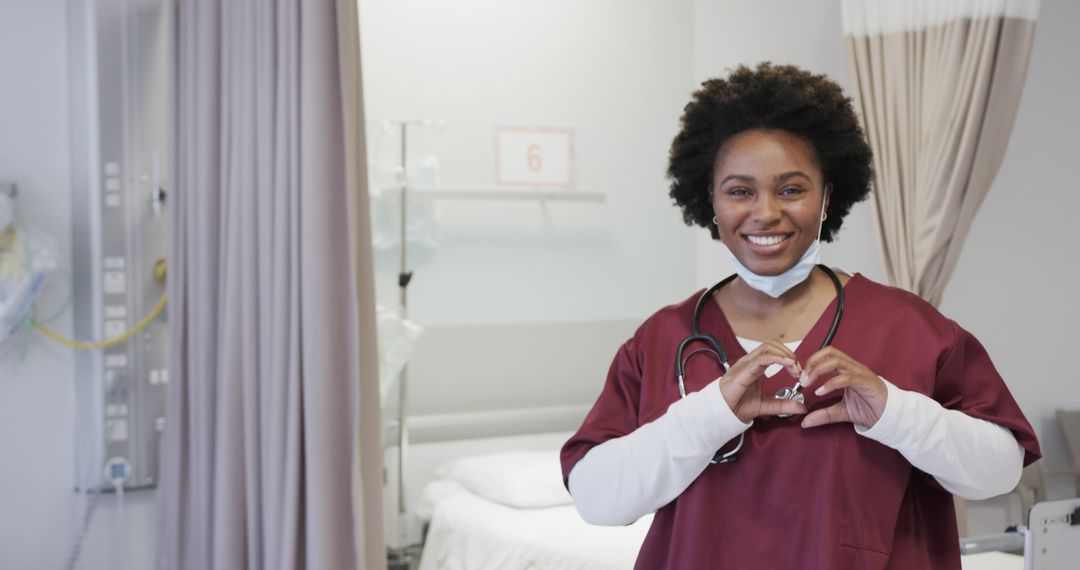 Smiling African American Nurse with Heart Gesture in Hospital Room - Free Images, Stock Photos and Pictures on Pikwizard.com