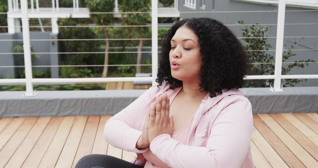 Plus-size woman practicing rooftop meditation and deep breathing in pink activewear