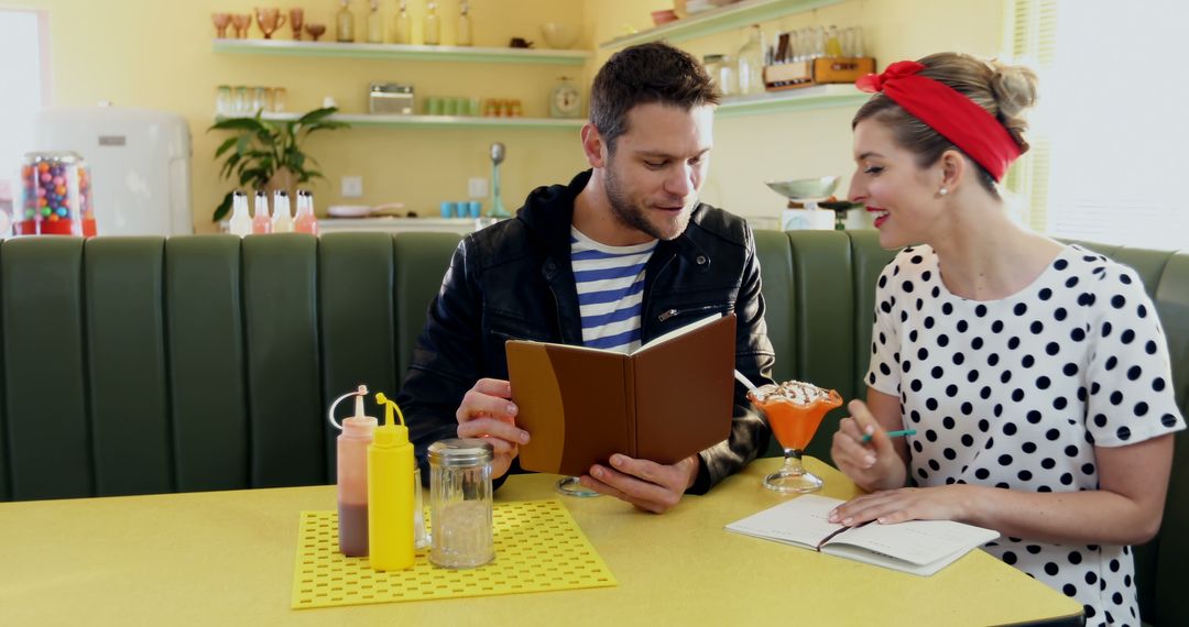 Happy caucasian couple looking at menu sitting at table in sunny retro diner, copy space - Free Images, Stock Photos and Pictures on Pikwizard.com