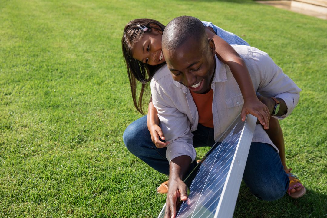 Father and Daughter Exploring Portable Solar Panel in Backyard