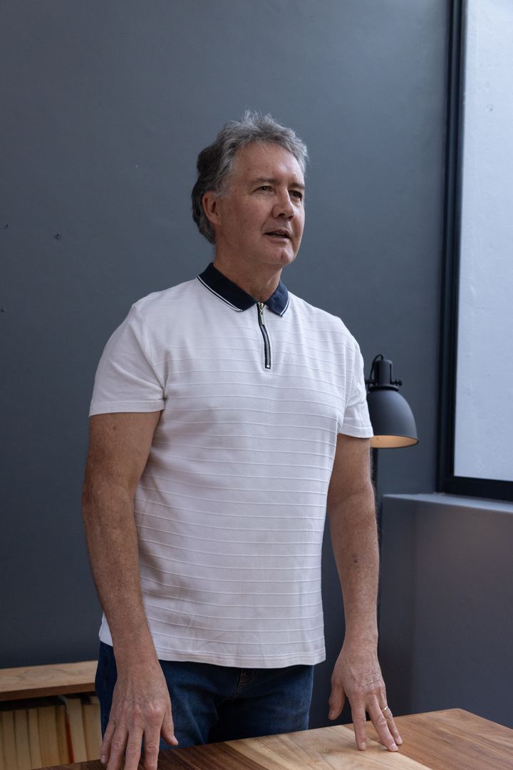 Senior Man Reflecting by Window in Minimalist Interior