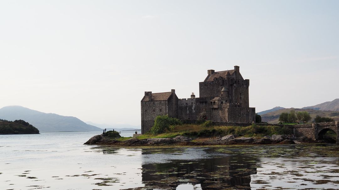 Historic Scottish Castle on Serene Lake with Mountain Background - Free Images, Stock Photos and Pictures on Pikwizard.com