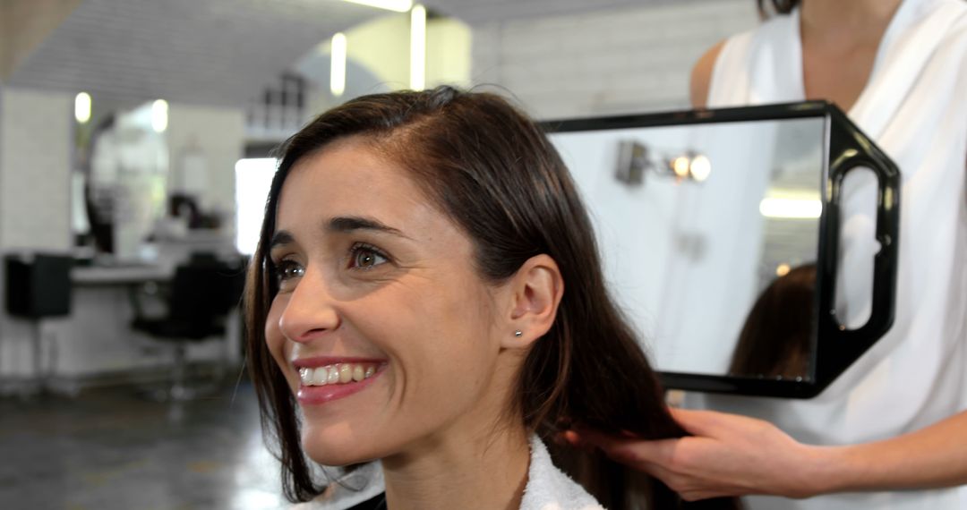 Smiling Woman Admiring Fresh Haircut in Modern Salon - Free Images, Stock Photos and Pictures on Pikwizard.com