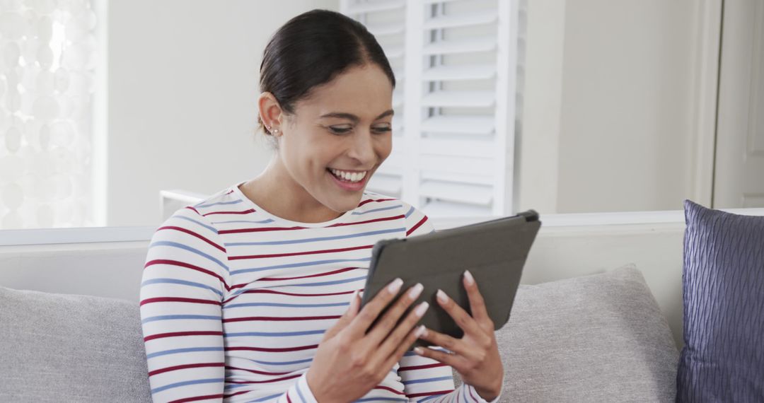 Smiling Woman Using Tablet While Sitting on Couch - Free Images, Stock Photos and Pictures on Pikwizard.com