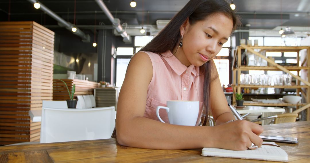 Young Woman Writing Notes in Coffee Shop During Daytime - Free Images, Stock Photos and Pictures on Pikwizard.com