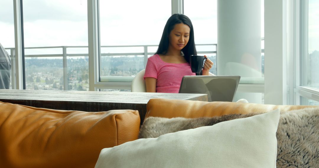 Woman Relaxing with Coffee and Laptop in Modern High-rise Apartment - Free Images, Stock Photos and Pictures on Pikwizard.com