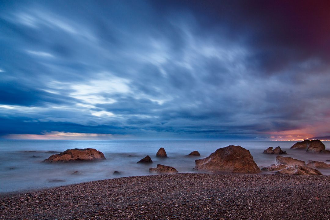 Serene Seascape with Rocks and Dramatic Clouds at Twilight - Free Images, Stock Photos and Pictures on Pikwizard.com