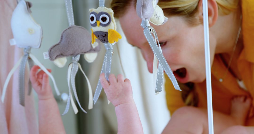 Mother Interacting with Baby in Crib, Reaching for Hanging Toys - Free Images, Stock Photos and Pictures on Pikwizard.com