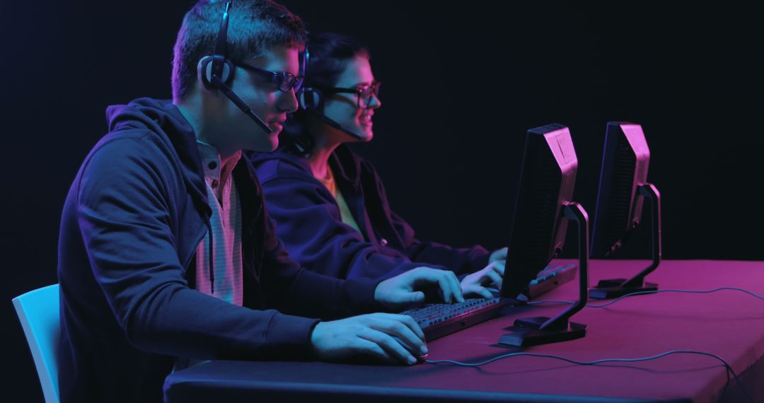 Focused Gamers Engaging with Computers Under Neon Light
