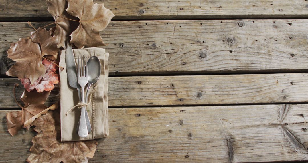 Rustic Autumn Table Setting with Silverware and Brown Leaves on Wooden Surface - Free Images, Stock Photos and Pictures on Pikwizard.com