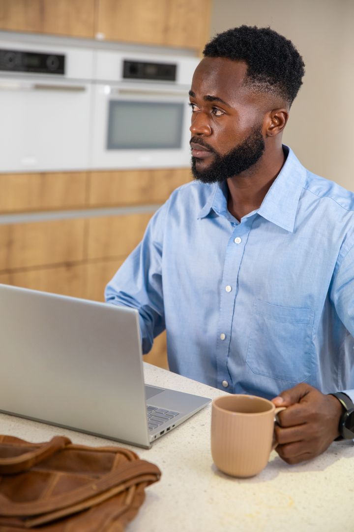 Focused Man Using Laptop while Enjoying Coffee at Home
